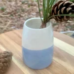 Vase en porcelaine bicolore blanc et bleu clair avec branche de pin