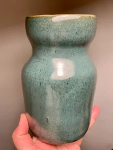 Vase en céramique émaillée vert moucheté tenu à la main