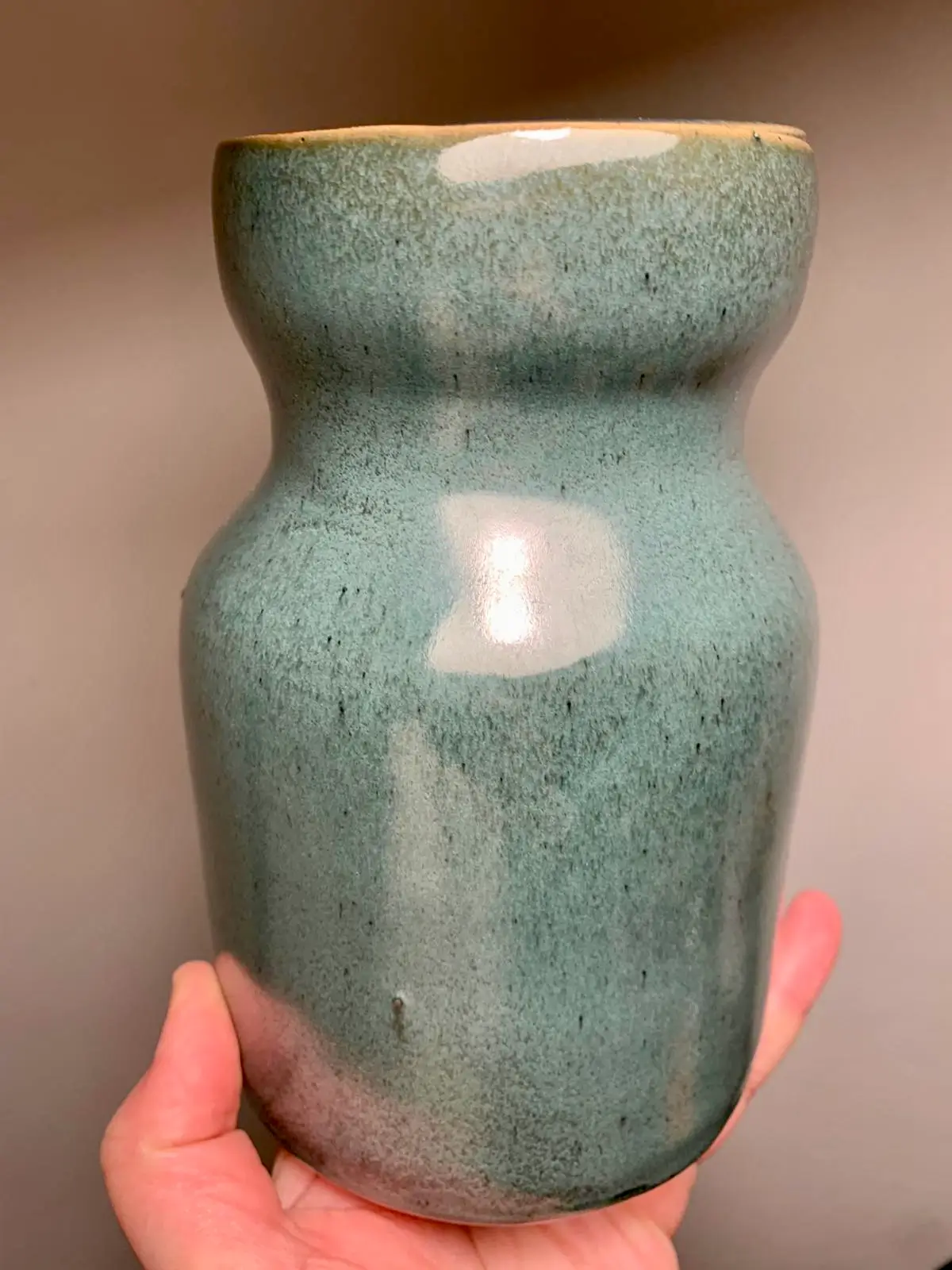 Vase en céramique émaillée vert moucheté tenu à la main